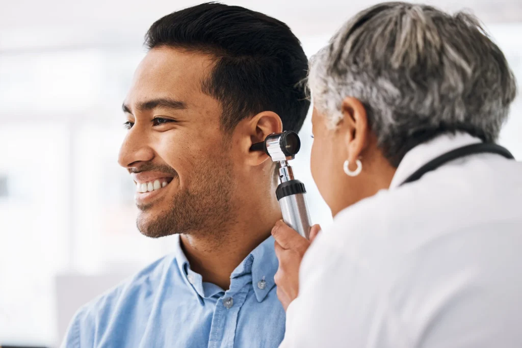 Patient undergoing a hearing test at their first audiologist appointment with a professional explaining the process. - Adirondack Audiology