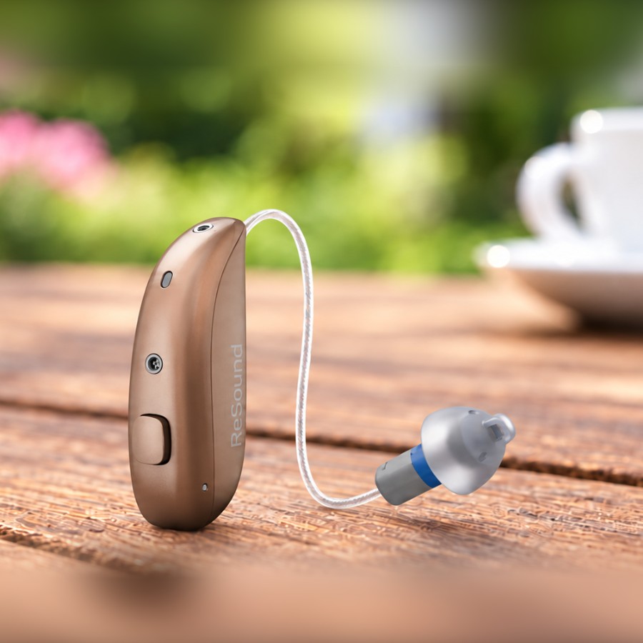 Rechargeable receiver-in-canal hearing aid on an outdoor table